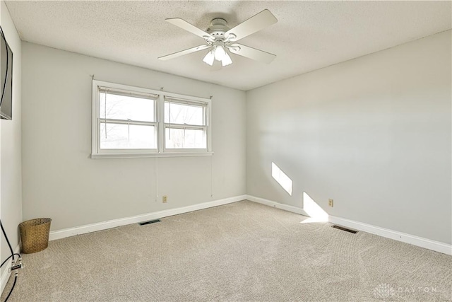 spare room featuring baseboards, a ceiling fan, visible vents, and carpet