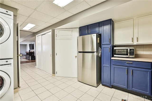 laundry room featuring stacked washer and dryer, laundry area, and light tile patterned floors