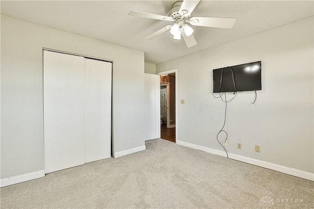 unfurnished bedroom with baseboards, a ceiling fan, carpet flooring, and a closet