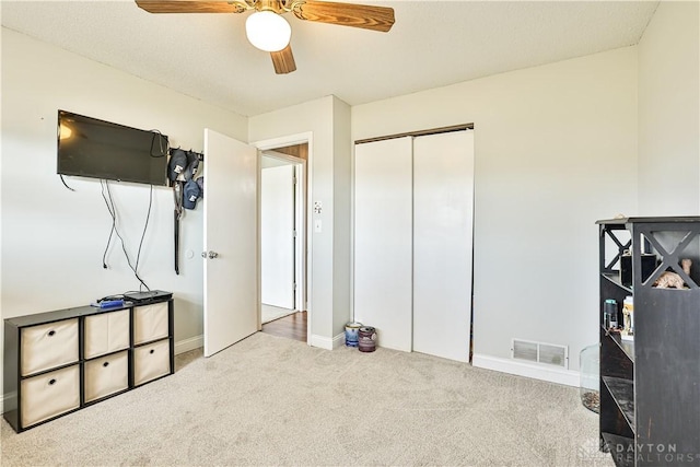 carpeted bedroom featuring ceiling fan, baseboards, visible vents, and a closet