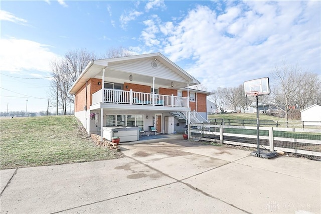 view of front of home with stairway, a front lawn, driveway, brick siding, and a hot tub