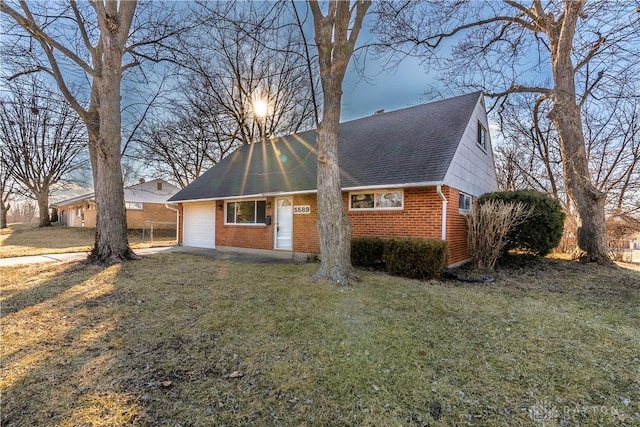 view of front of property with a garage, driveway, brick siding, roof with shingles, and a front yard