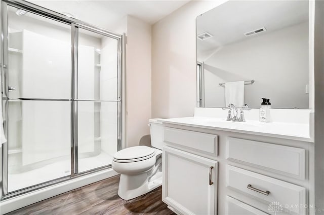 full bath featuring visible vents, toilet, wood finished floors, vanity, and a shower stall