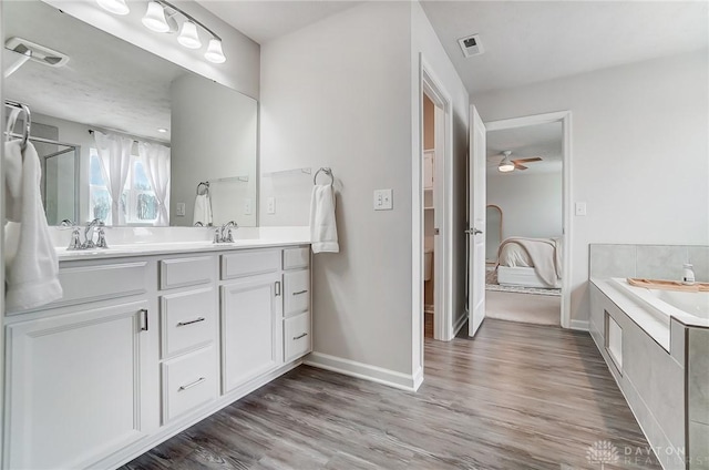 ensuite bathroom featuring double vanity, visible vents, connected bathroom, a sink, and wood finished floors