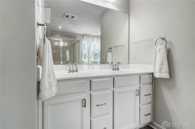 full bath with double vanity, a stall shower, visible vents, and a sink