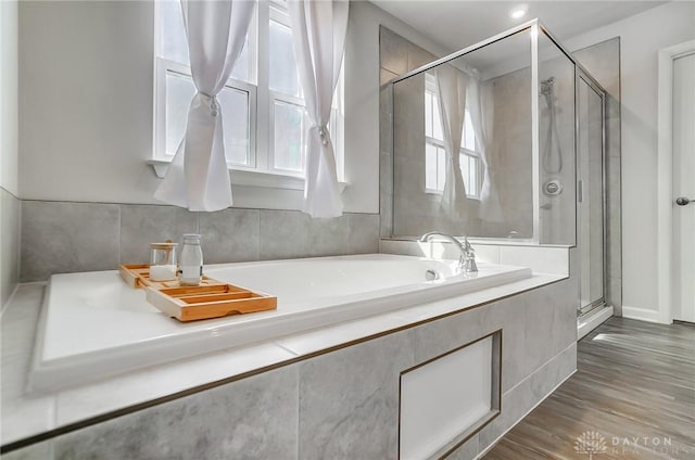 bathroom with a garden tub, wood finished floors, and a shower stall