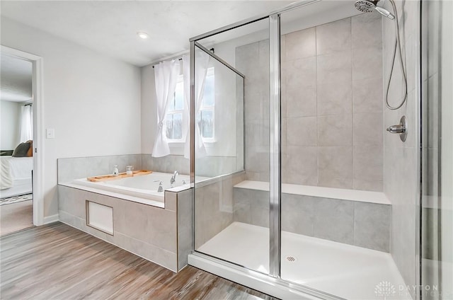 ensuite bathroom featuring a stall shower, ensuite bathroom, a bath, and wood finished floors