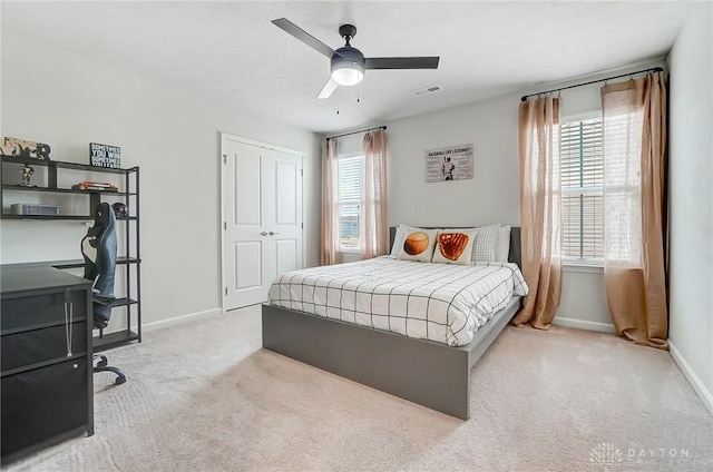 bedroom featuring baseboards, visible vents, light colored carpet, ceiling fan, and a closet