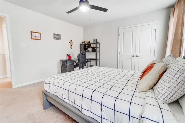 bedroom with light carpet, ceiling fan, a closet, and baseboards