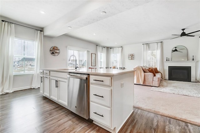 kitchen with an island with sink, open floor plan, light countertops, white cabinetry, and stainless steel dishwasher