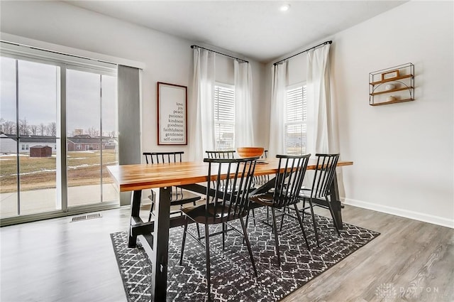 dining room featuring wood finished floors, visible vents, and baseboards