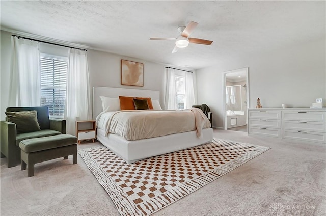 bedroom featuring a ceiling fan, light colored carpet, a textured ceiling, and ensuite bath