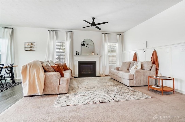 living room featuring a glass covered fireplace and ceiling fan