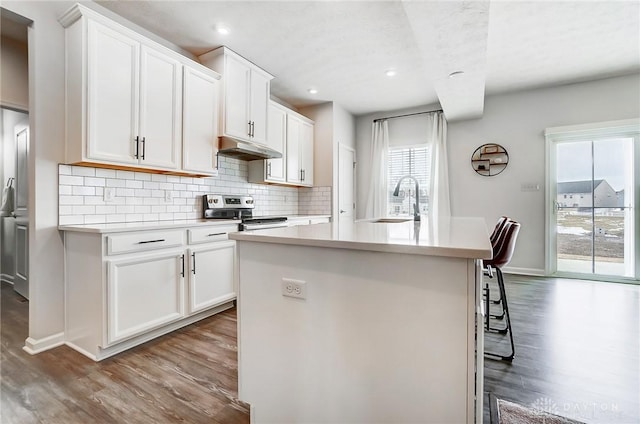 kitchen featuring light countertops, a kitchen island with sink, white cabinets, and stainless steel electric stove