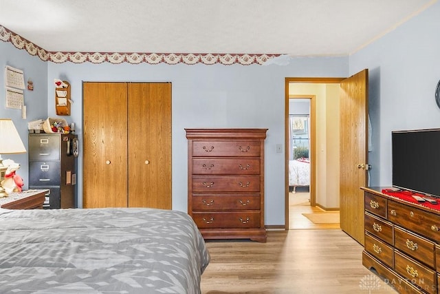 bedroom with a closet, light wood-type flooring, and baseboards