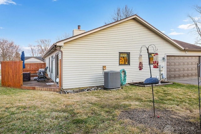 view of side of home featuring central AC unit, a lawn, a chimney, and fence