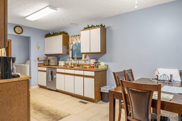 kitchen with white cabinetry, a textured ceiling, washer and dryer, and a sink