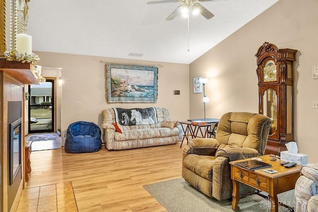 living room featuring vaulted ceiling, light wood finished floors, visible vents, and a ceiling fan