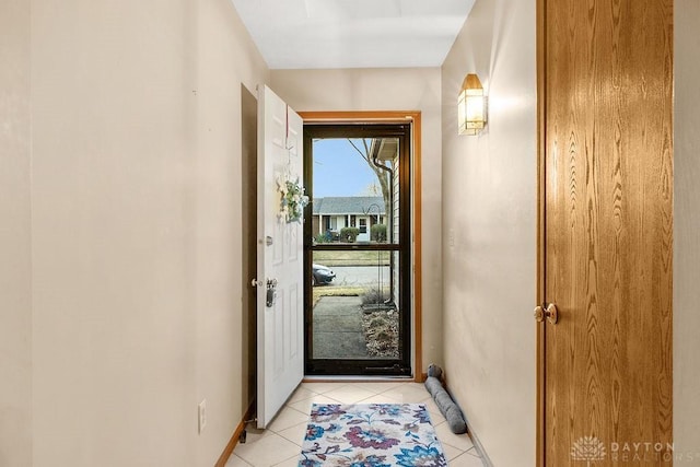 doorway with baseboards and light tile patterned floors