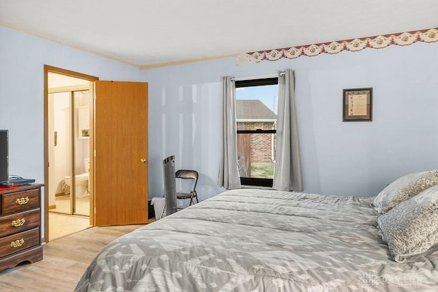 bedroom with light wood-style flooring, connected bathroom, and crown molding