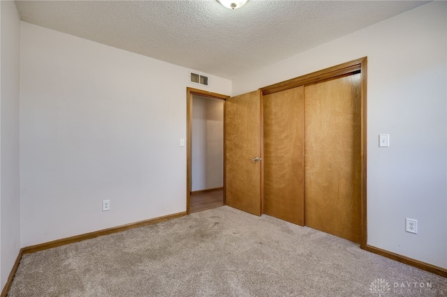 unfurnished bedroom featuring carpet, a closet, a textured ceiling, and baseboards