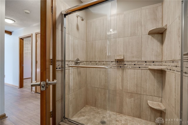 full bathroom with a textured ceiling, a stall shower, and wood finished floors