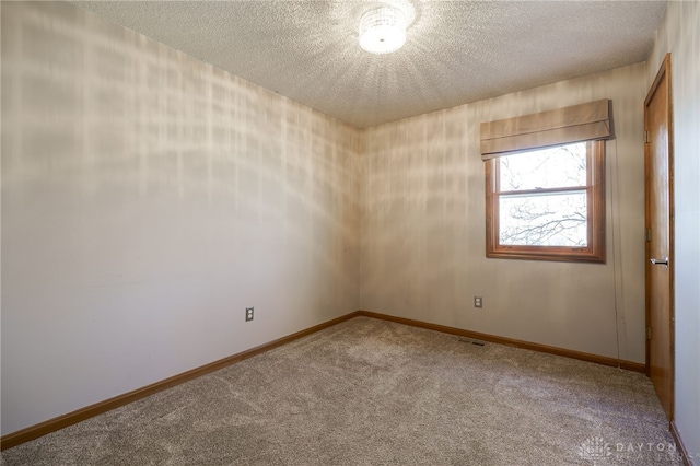 carpeted spare room featuring baseboards and a textured ceiling