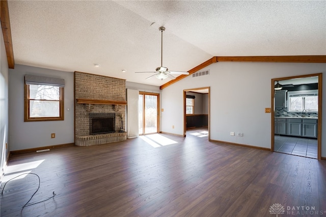 unfurnished living room featuring visible vents, a ceiling fan, dark wood-style flooring, vaulted ceiling, and a brick fireplace