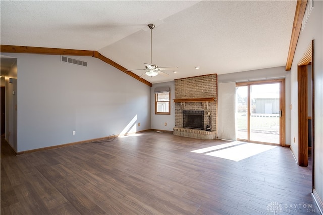 unfurnished living room featuring a wealth of natural light, a brick fireplace, visible vents, and vaulted ceiling