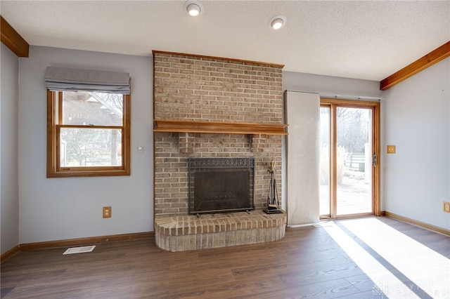 unfurnished living room featuring baseboards, a textured ceiling, visible vents, and wood finished floors