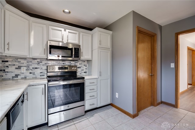 kitchen featuring stainless steel appliances, tasteful backsplash, light tile patterned flooring, and white cabinets