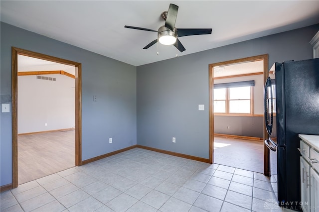 kitchen with light tile patterned floors, visible vents, baseboards, ceiling fan, and freestanding refrigerator