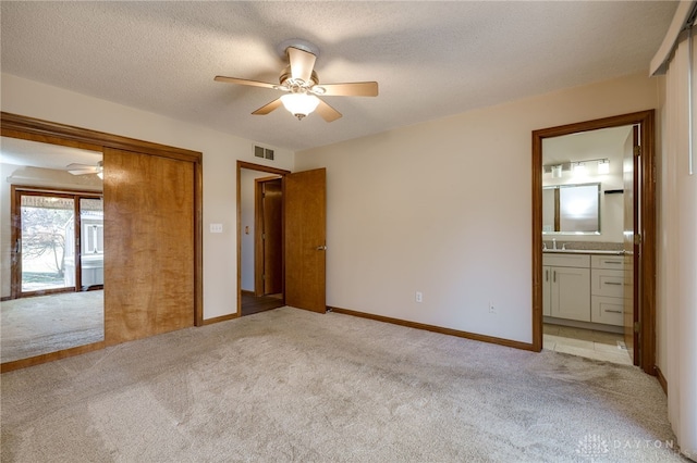 unfurnished bedroom featuring baseboards, visible vents, light carpet, and a textured ceiling