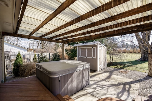 view of patio featuring fence, an outdoor structure, a hot tub, and a shed