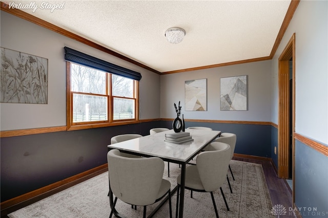 dining area featuring ornamental molding, a textured ceiling, baseboards, and wood finished floors