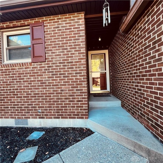 entrance to property featuring crawl space and brick siding