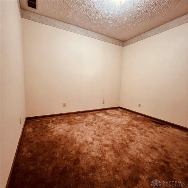 unfurnished room with a textured ceiling, carpet floors, visible vents, and baseboards