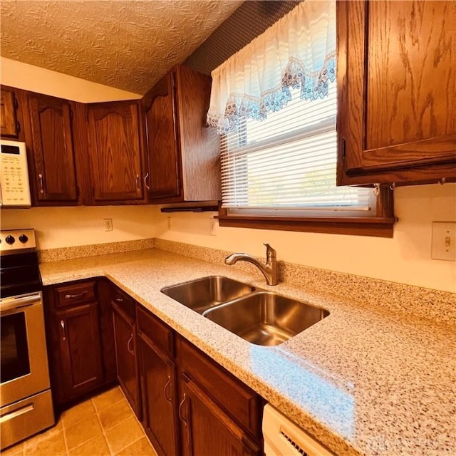 kitchen featuring a textured ceiling, light tile patterned floors, white microwave, a sink, and stainless steel electric stove