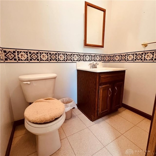 half bath featuring baseboards, vanity, and toilet