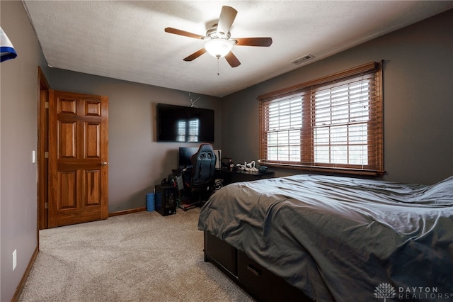 bedroom with baseboards, visible vents, a ceiling fan, light colored carpet, and a textured ceiling