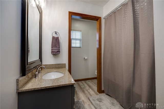 full bathroom with baseboards, vanity, toilet, and wood finished floors