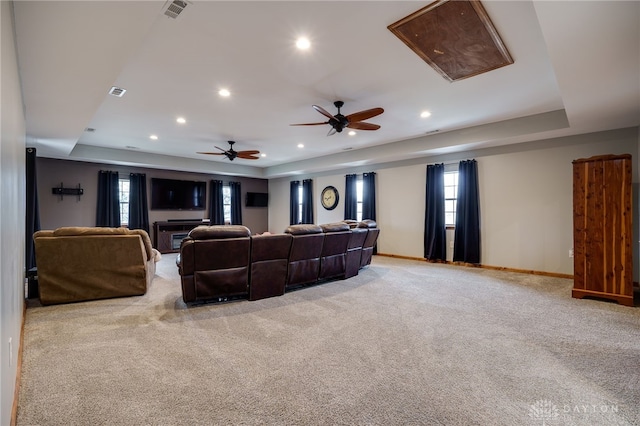 carpeted living area with a wealth of natural light, a raised ceiling, visible vents, and baseboards