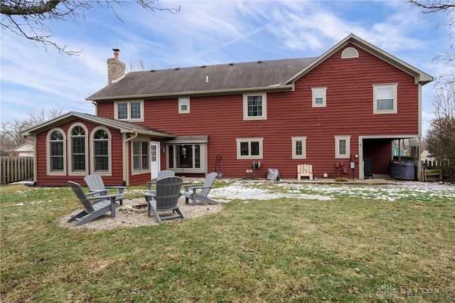 rear view of house featuring an outdoor fire pit, a yard, a chimney, and fence