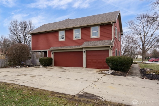 view of front of home with a garage, fence, driveway, and a shingled roof