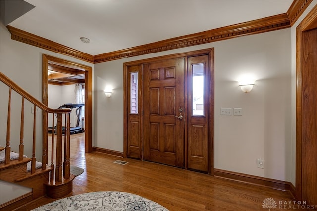 foyer with visible vents, baseboards, stairway, wood finished floors, and crown molding