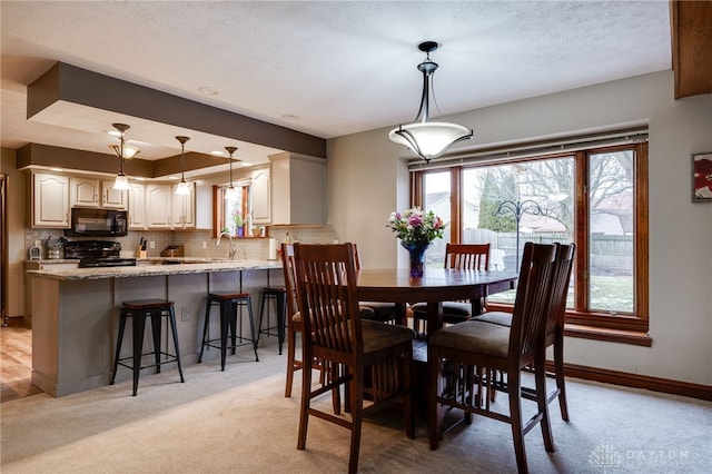 dining area featuring light carpet, a textured ceiling, and baseboards