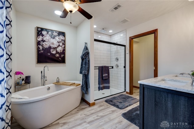 full bathroom with visible vents, wood finished floors, a freestanding bath, a shower stall, and a sink