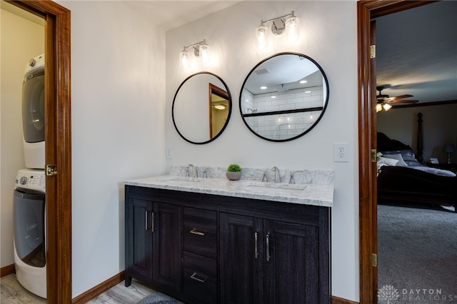 ensuite bathroom with double vanity, stacked washing maching and dryer, ensuite bath, and a sink