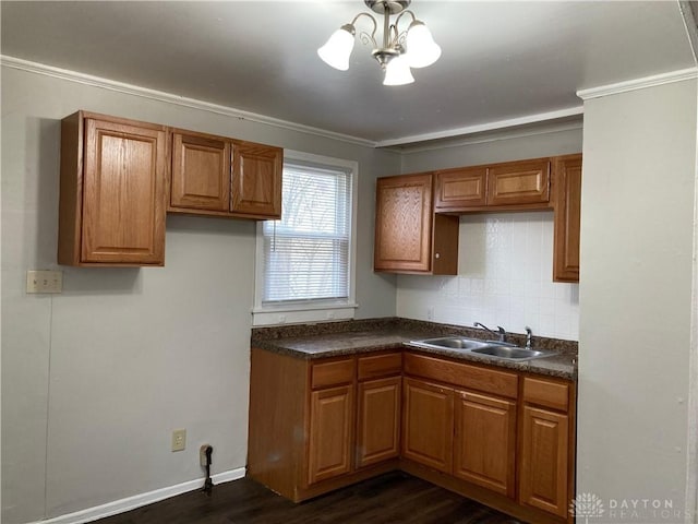 kitchen featuring dark wood-style flooring, brown cabinets, dark countertops, backsplash, and a sink