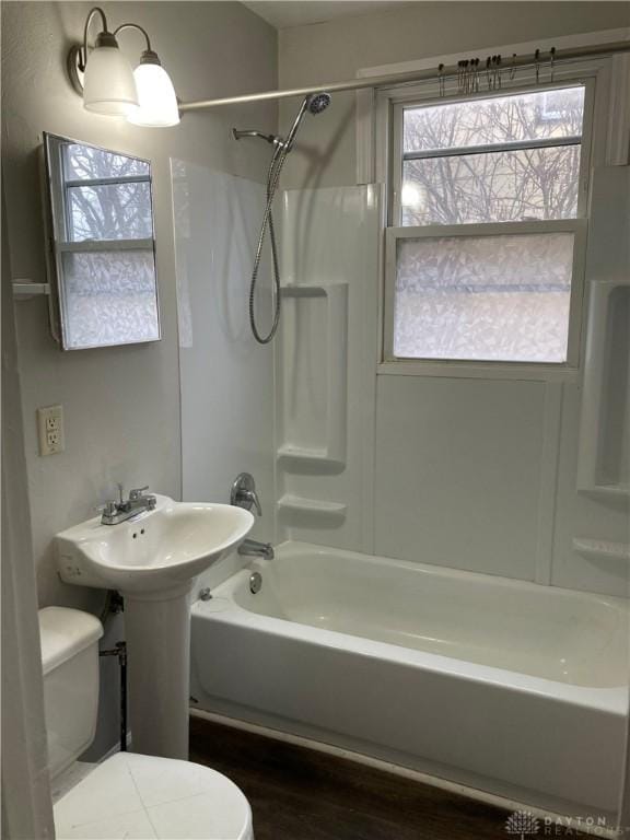 bathroom featuring bathtub / shower combination, toilet, and wood finished floors